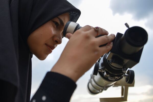 Девушка смотрит в телескоп в поиске новолуния - Sputnik Азербайджан