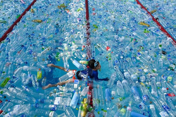 Ребенок плавает в бассейне, наполненном пластиковыми бутылками, во время информационной кампании, посвященной Всемирному дню океанов в Бангкоке, Таиланд - Sputnik Азербайджан