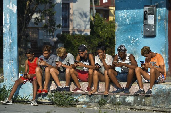 Молодые кубинцы с мобильными телефонами на улице Гаваны - Sputnik Азербайджан