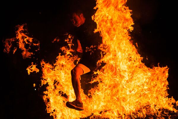 Мужчина прыгает через костер на праздновании Ночи святого Хуана в Испании - Sputnik Азербайджан