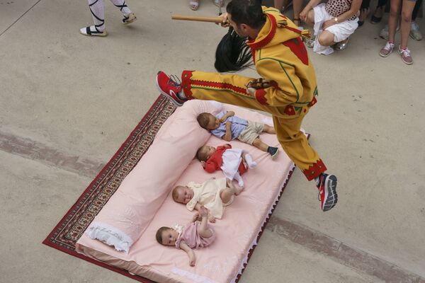 Мужчина, одетый в костюм дьявола, перепрыгивает через младенцев во время ежегодного фестиваля Эль Колачо в испанском городе Кастильо де Мурсия - Sputnik Азербайджан