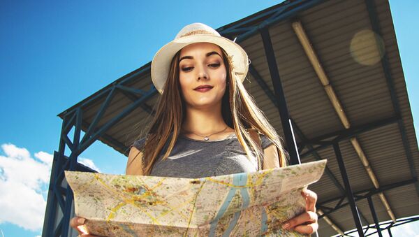 Симпатичная девушка рассматривает карту и обдумывает маршрут своего путешествия - Sputnik Азербайджан