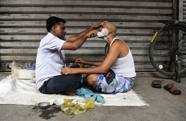Парикмахер бреет клиента в старом квартале Нью-Дели, Индия - Sputnik Азербайджан