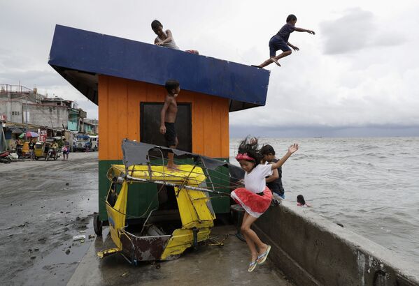 Дети прыгают в воду в бухте Манилы на Филиппинах после сильного ливня - Sputnik Азербайджан