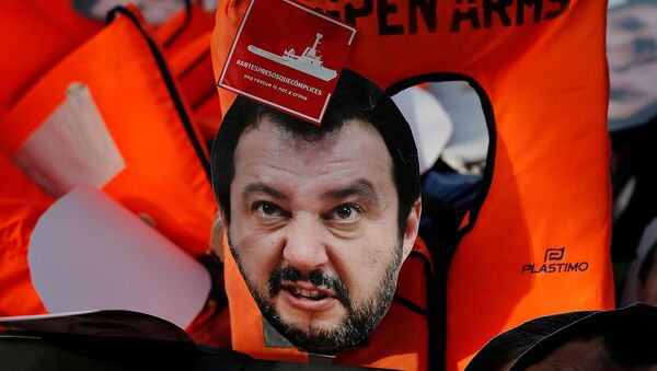 Маска министра внутренних дел Италии Маттео Сальвини лежит на спасательных жилетах, когда протестующие маршируют во время демонстрации против криминализации миссий по спасению мигрантов - Sputnik Азербайджан