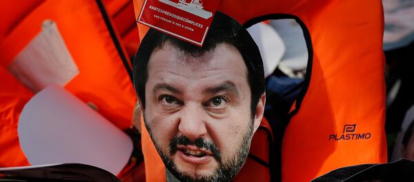 Маска министра внутренних дел Италии Маттео Сальвини лежит на спасательных жилетах, когда протестующие маршируют во время демонстрации против криминализации миссий по спасению мигрантов - Sputnik Азербайджан