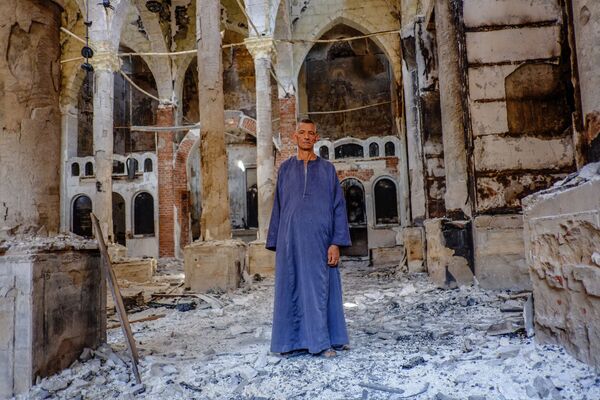Копт в одной из сожженных и разрушенных коптских церквей в провинции Минья - Sputnik Азербайджан