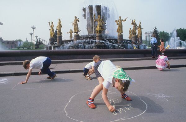 Дети рисуют мелом на асфальте у фонтана Дружба народов в Москве. 1984 - Sputnik Азербайджан