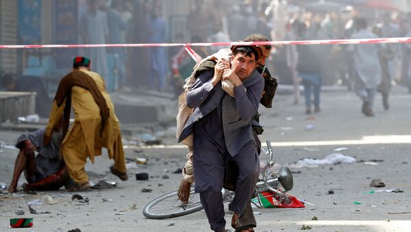 Мужчина несет на себе раненого человека в больницу после взрыва в Джелалабаде, Афганистан - Sputnik Azərbaycan