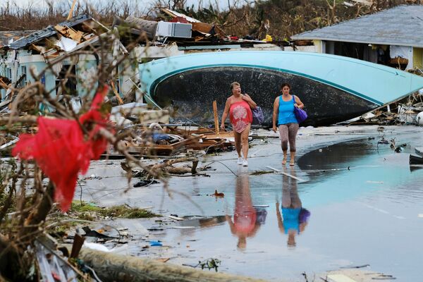Женщины идут по завалам после урагана Дориан на острове Грейт-Абако в Марш-Харборе, Багамские острова - Sputnik Азербайджан