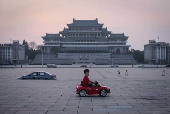 Мальчик на игрушечной машине на площади Ким Ир Сена в Пхеньяне, Северная Корея - Sputnik Азербайджан