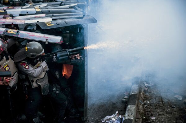 Полицейский применяет слезоточивый газ во время столкновения со студенческими демонстрантами в Бандунге, Индонезия - Sputnik Азербайджан