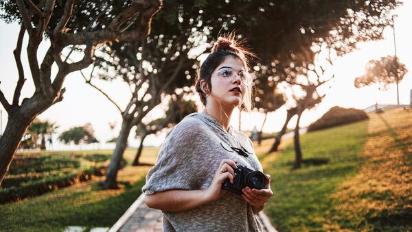 Симпатичная девушка в очках гуляет по осеннему парку с фотокамерой - Sputnik Азербайджан