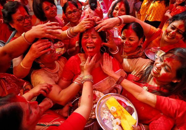Нанесение цветного порошка на лицо индийской женщины в честь поклонения индуистской богине Дурги на фестивале Durga Puja в Чандигархе, Индия - Sputnik Азербайджан