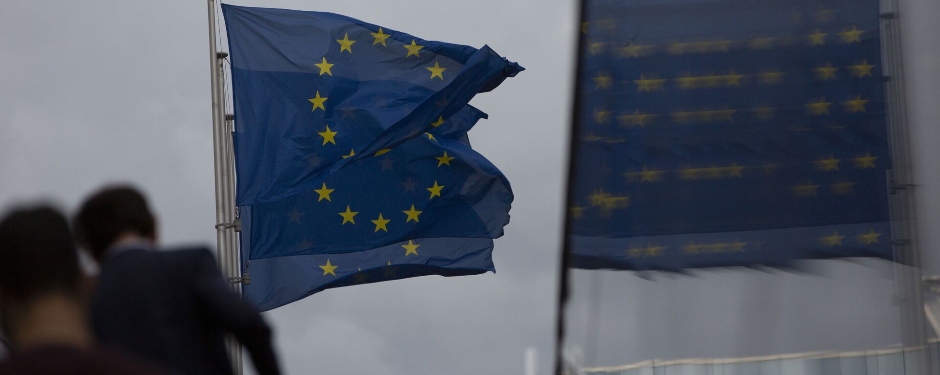 Флаги Европейского Союза развеваются на ветру, когда два человека поднимаются по лестнице возле штаб-квартиры ЕС в Брюсселе - Sputnik Azərbaycan, 1920, 27.01.2021