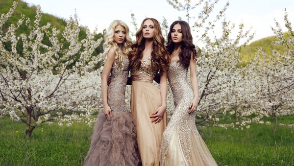 Три красивые девушки с длинными волосами и макияжем, одетые в вечерние платья, позируют в весеннем саду - Sputnik Азербайджан