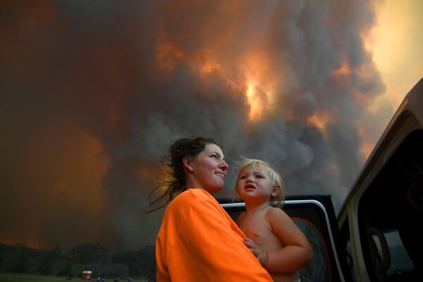Женщина в ребенком на руках в дыму природных пожаров в Австралии - Sputnik Азербайджан