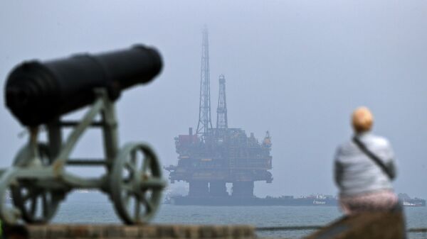 Мужчина смотрит на нефтяную платформу Brent Delta у побережья Хартлпула на северо-востоке Англии - Sputnik Азербайджан