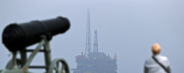 Мужчина смотрит на нефтяную платформу Brent Delta у побережья Хартлпула на северо-востоке Англии - Sputnik Азербайджан