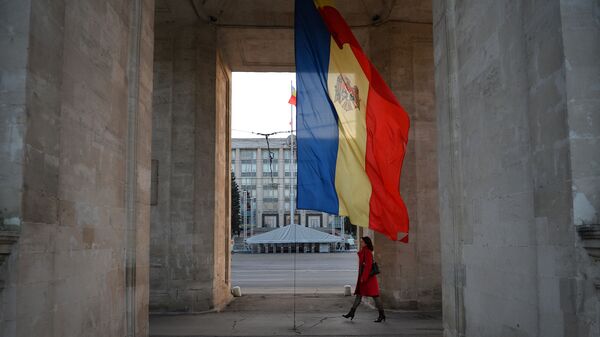 Женщина идет под Триумфальной аркой рядом с молдавским флагом в Кишиневе - Sputnik Azərbaycan
