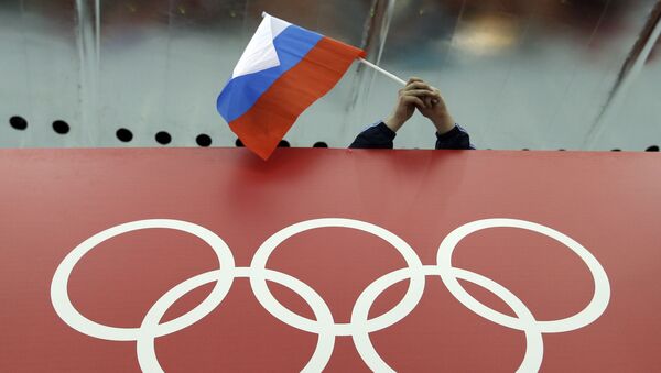 Российский фанат держит национальный флаг страны над олимпийскими кольцами - Sputnik Азербайджан