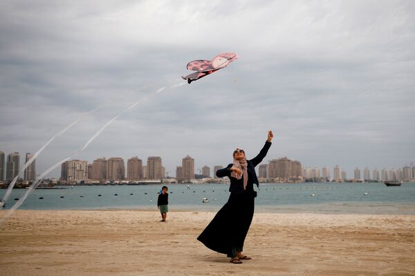 Женщина в мусульманской одежде с воздушным змеем на пляже в Дохе, Катар - Sputnik Азербайджан