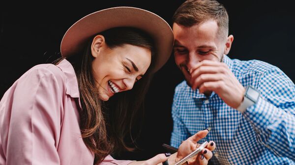 Счастливая влюбленная пара смотрит смешное видео на смартфоне - Sputnik Азербайджан