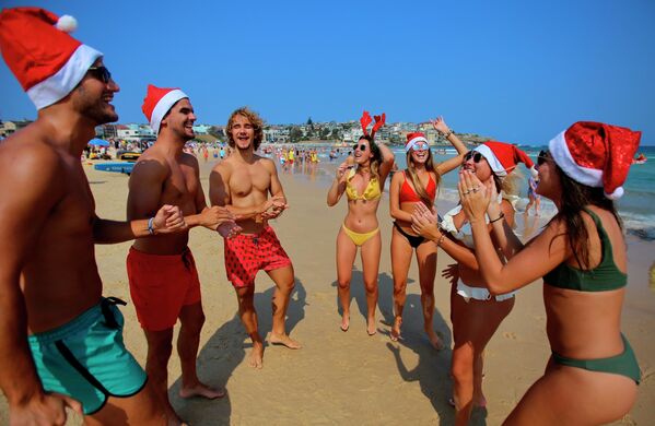 Туристы в рождественских костюмах на пляже в Сиднее - Sputnik Азербайджан