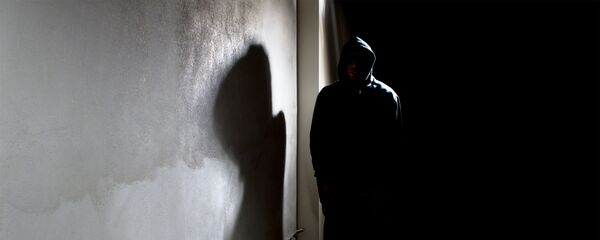 Мужчина в капюшоне прячется в тени улицы Мужчина в капюшоне прячется в тени улицы - Sputnik Азербайджан