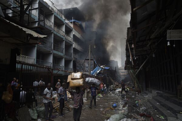 Люди несут товары, спасенные от пожара, в районе рынка Балогун в Лагосе - Sputnik Азербайджан