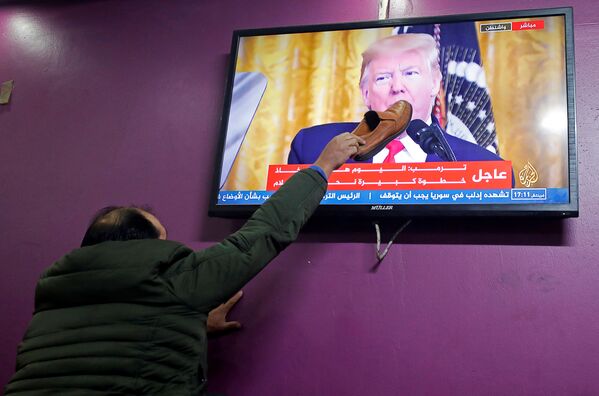 Палестинец прикладывает ботинок к экрану телевизора в кафе города Хеврон, по которому Дональд Трамп рассказывает о своем плане ближневосточного урегулирования - Sputnik Азербайджан