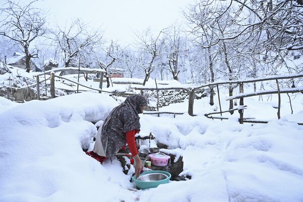Женщина моет посуду на окраине Сринагара, где выпал снег - Sputnik Азербайджан