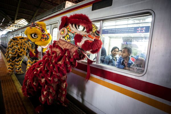  Пассажиры смотрят из окна поезда на праздничных львов во время празднования китайского лунного Нового года в Джакарте, Индонезия - Sputnik Азербайджан