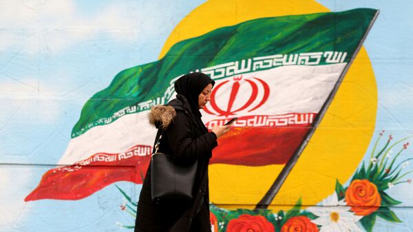 Женщина проходит перед фреской, на которой изображен иранский национальный флаг, фото из архива - Sputnik Азербайджан