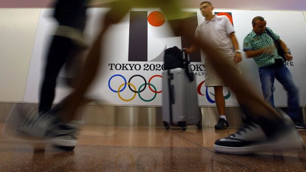 Туристы проходят мимо плаката с логотипом Олимпиады в Токио, фото из архива - Sputnik Azərbaycan