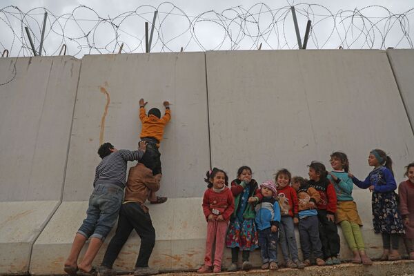 Сирийские дети пытаются перебраться через турецкую пограничную стену в северо-западной провинции Сирии - Sputnik Азербайджан