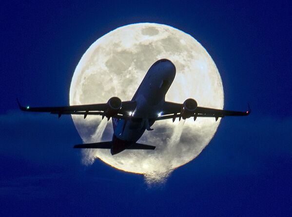 An aircraft passes the rising full moon  - Sputnik Азербайджан