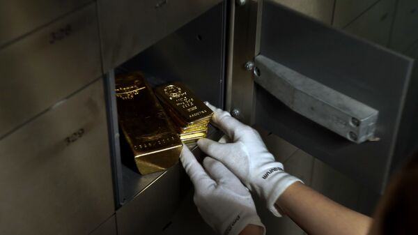 Сотрудник банка кладет золотые слитки в сейф, фото из архива - Sputnik Азербайджан