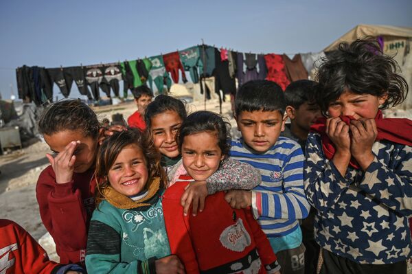 Displaced Syrian children pose for a picture at a camp created by Turkey's Humanitarian Relief Foundation (IHH) in Kafr Lusin village on the border with Turkey in Syria's northwestern province of Idlib - Sputnik Азербайджан