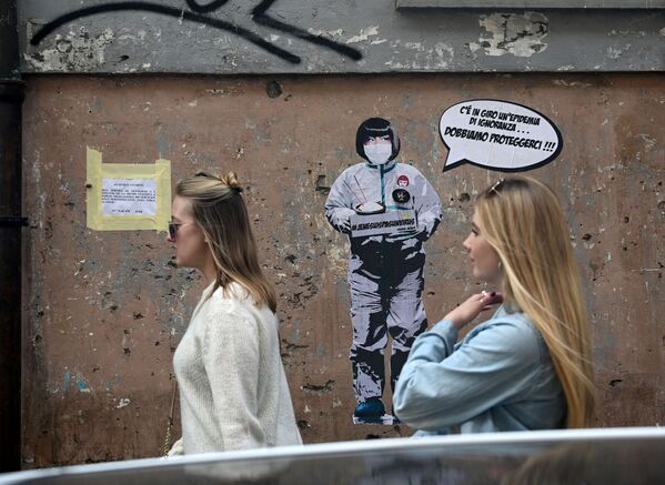 Девушки на фоне стены с граффити на тему коронавируса художника Laika в Риме - Sputnik Азербайджан