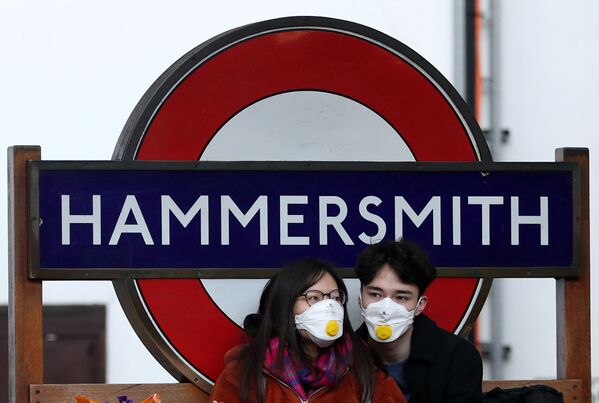 Пара в защитных масках у станции метро Hammersmith в Лондоне - Sputnik Азербайджан