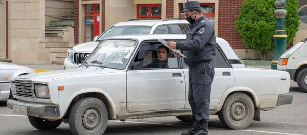 Ağstafada polis əməkdaşı sürücünün xüsusi rejim zamanı fəaliyyət göstərməsinə icazə verən sənədi yoxlayır - Sputnik Азербайджан