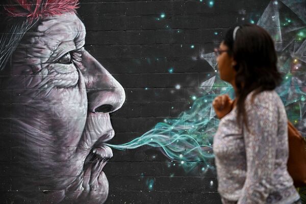 Женщина проходит мимо граффити, нарисованного в рамках фестиваля Graficalia в Кали, Колумбия - Sputnik Azərbaycan