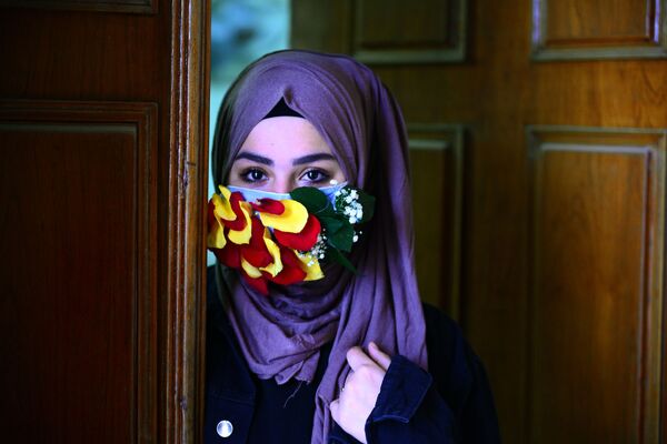 A woman is seen wearing a mask embellished with petals in the central Iraqi holy city of Najaf on March 21, 2020 amid the COVID-19 coronavirus pandemic.   - Sputnik Азербайджан