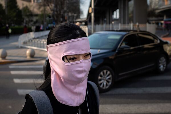 A woman wearing a face mask amid the COVID-19 coronavirus outbreak walks outside office buildings in Beijing  - Sputnik Азербайджан