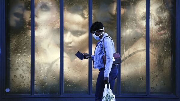 Женщина в защитной маске проходит мимо витрины магазина в Париже - Sputnik Azərbaycan