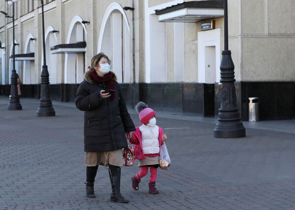 A woman with a child wearing protective masks as a preventive measure against coronavirus disease (COVID-19) walk near a closed central railway station in Kiev, Ukraine - Sputnik Азербайджан