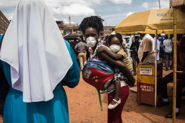 A mother and her child wear masks as a preventive measure agaisnt the COVID-19 coronavirus at a bus park in Kampala, Uganda, on March 20, 2020. - Sputnik Азербайджан