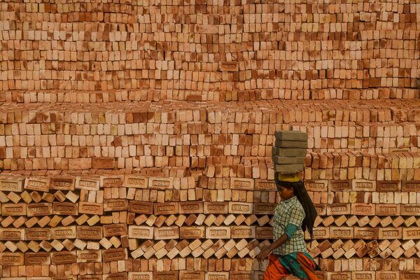 A migrant labourer carries bricks on the head while working at a brick kiln factory during a government-imposed nationwide lockdown as a preventive measure against the COVID-19 coronavirus, on the outskirts of Kolkata  - Sputnik Azərbaycan