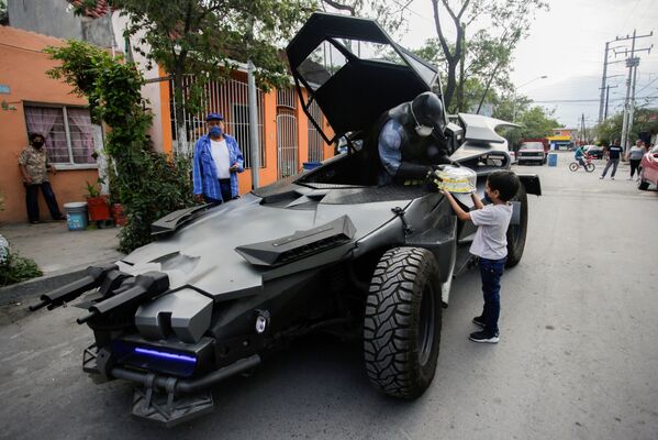 Mexican lawyer Candelario Maldonado, dressed up as the fictional character Batman, gives a birthday cake to a child wearing face mask in front of his home, during the global outbreak of the coronavirus disease (COVID-19), in Monterrey, Mexico - Sputnik Azərbaycan